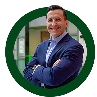 A business man smiles with his arms crossed in a green circle