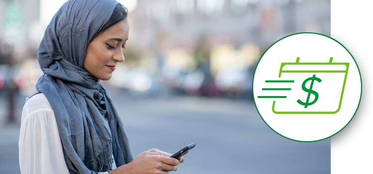 A woman looks at her phone while crossing the street