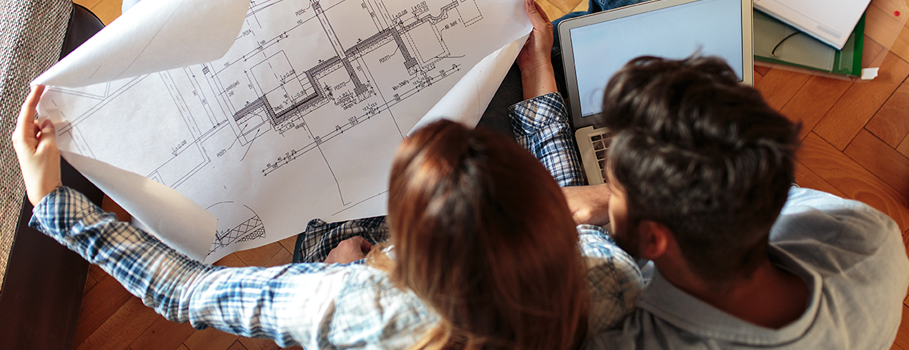 A couple looks at their homes blueprints for their upcoming renovations