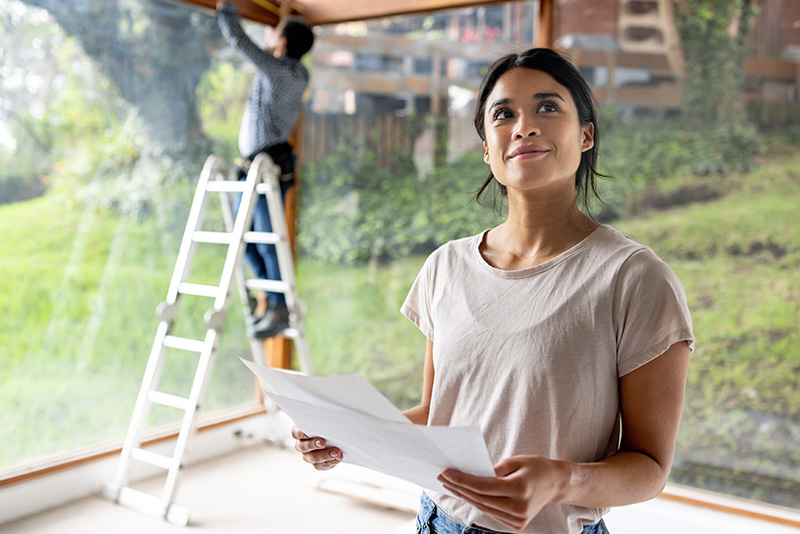 A woman looks at the blueprints of her home improvement project