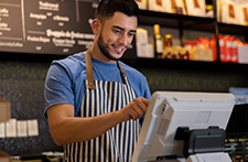 A barista types at the POS system at his work