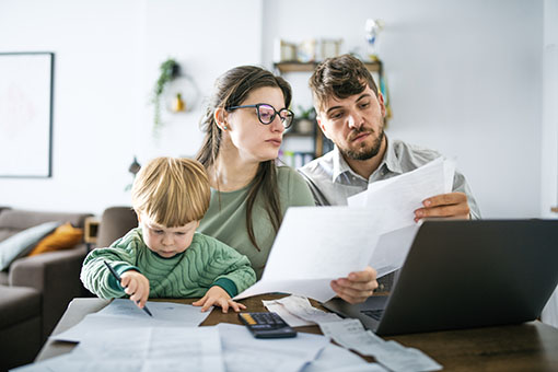 A married couple look at documents while the toddler draws on them