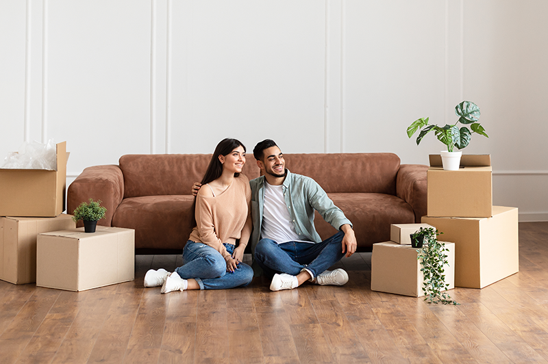A happy couple looks at their new home with moving boxes around them