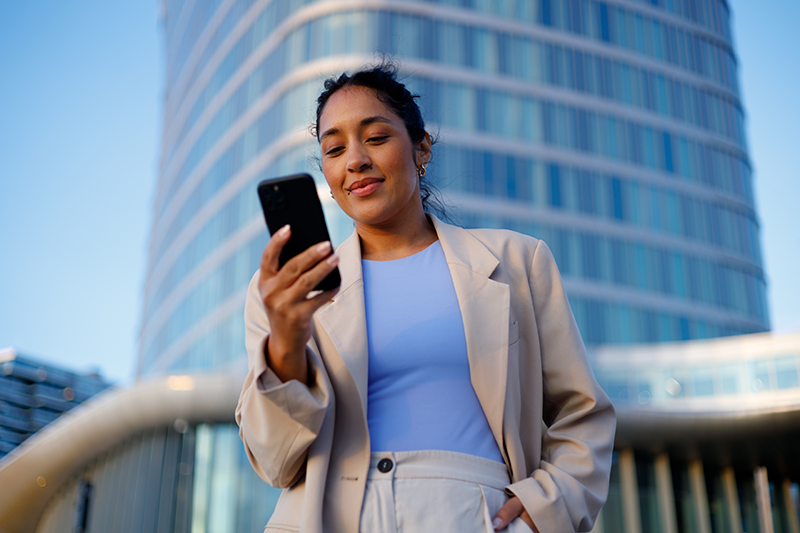 A business woman looks at her phone outside