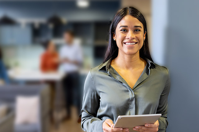 Happy businesswoman working on a digital tablet at the office